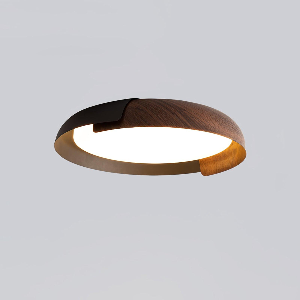A black and dark wood Clérachic ceiling light with a grey-brown inner rim, lit, on a pale grey backdrop.