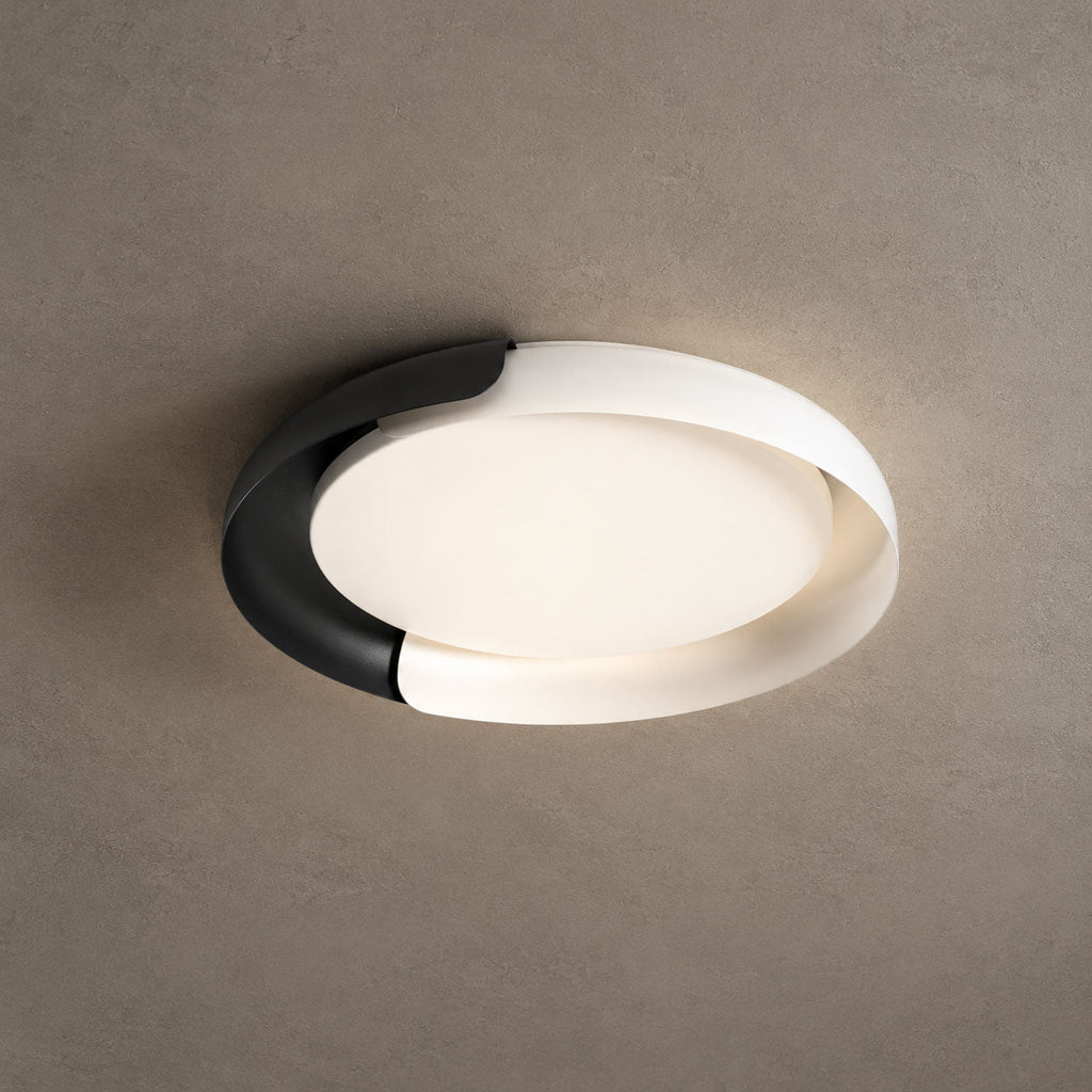 A white and black Clérachic ceiling light lit with a soft warm glow, against a textured stone-grey ceiling.