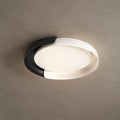 A white and black Clérachic ceiling light lit with a soft warm glow, against a textured stone-grey ceiling.