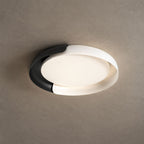 A white and black Clérachic ceiling light lit with a soft warm glow, against a textured stone-grey ceiling.