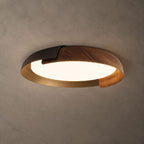 A black and dark wood Clérachic ceiling light with a gold-toned inner rim, lit, against a textured grey-brown ceiling.