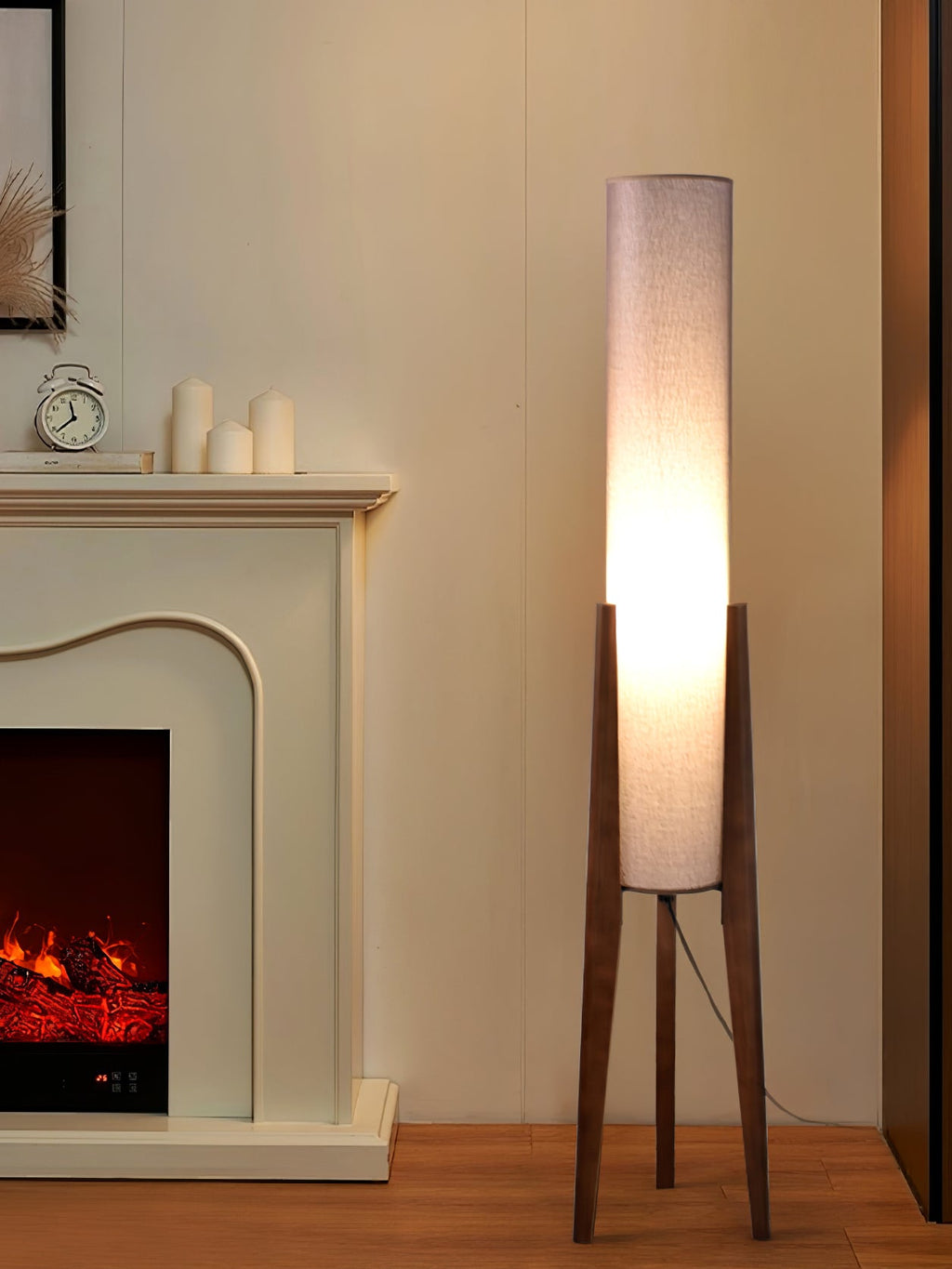 Clérachic floor lamp with a pale shade and walnut legs beside a fireplace with white candles on the mantel.