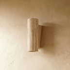 A closer view of the Clérachic wall lamp's round stone body and pale-wood base, its warm downlight glowing below.