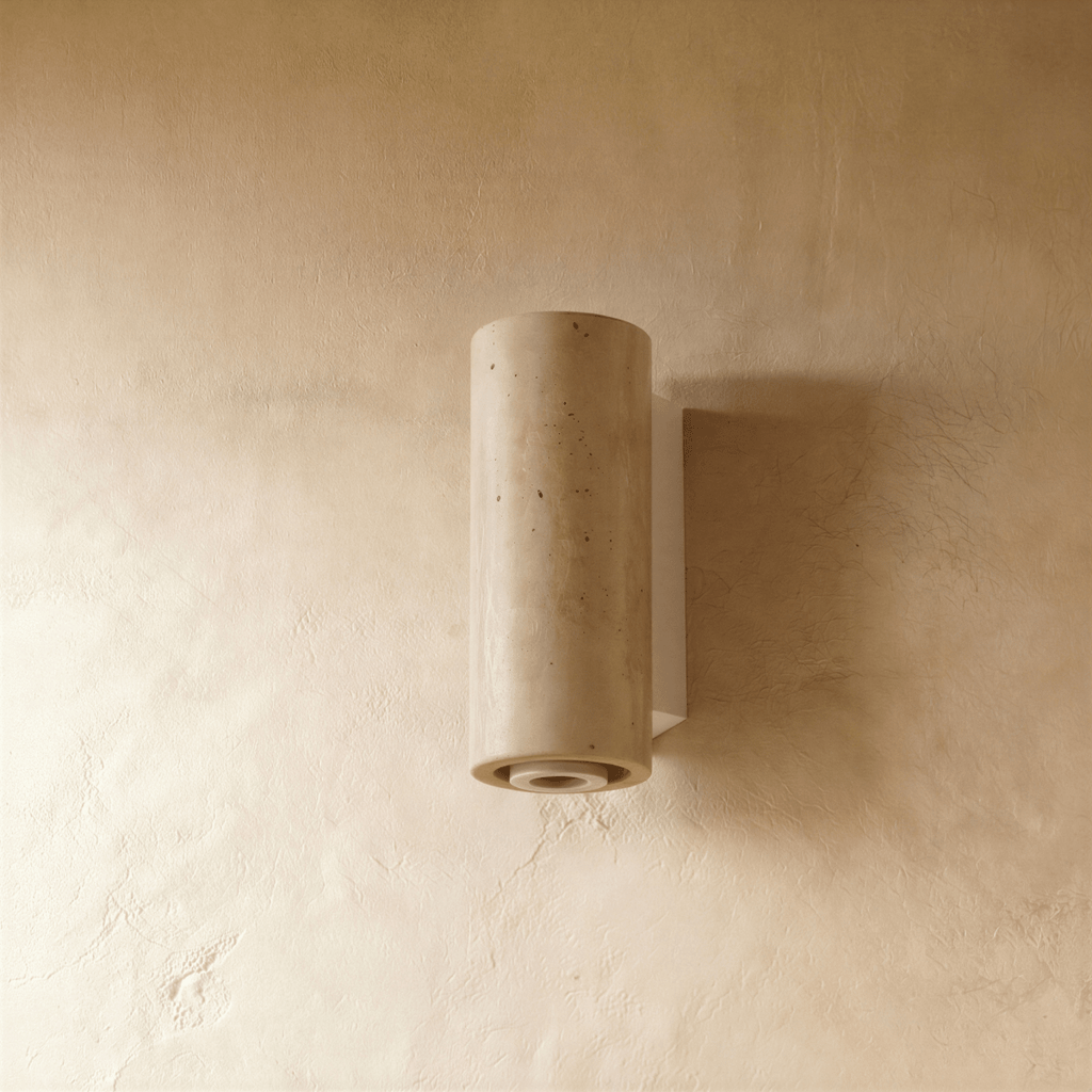The Clérachic wall lamp's cylindrical stone shade with its pale metal base, lit from below.