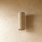 The Clérachic wall lamp's cylindrical stone shade with its pale metal base, lit from below.