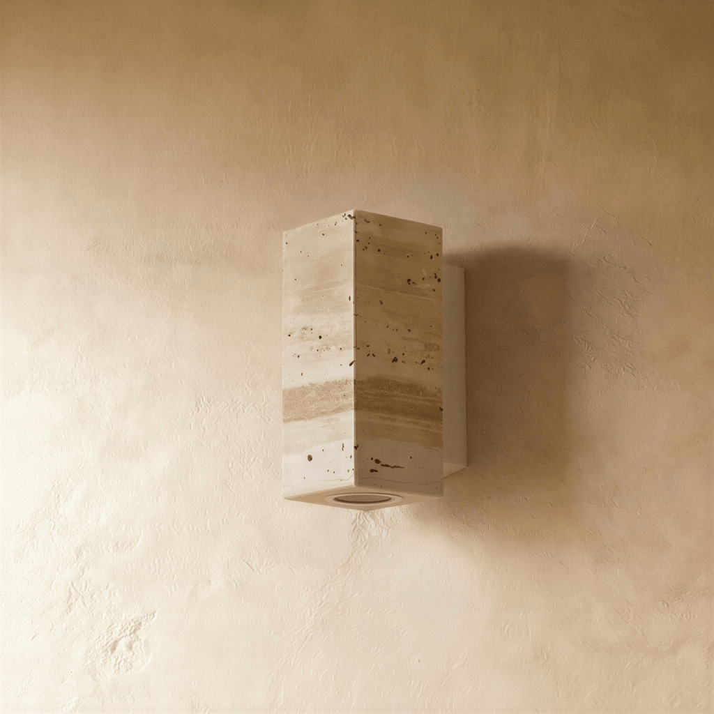 The Clérachic wall lamp's rectangular stone body viewed straight on against a plaster wall.