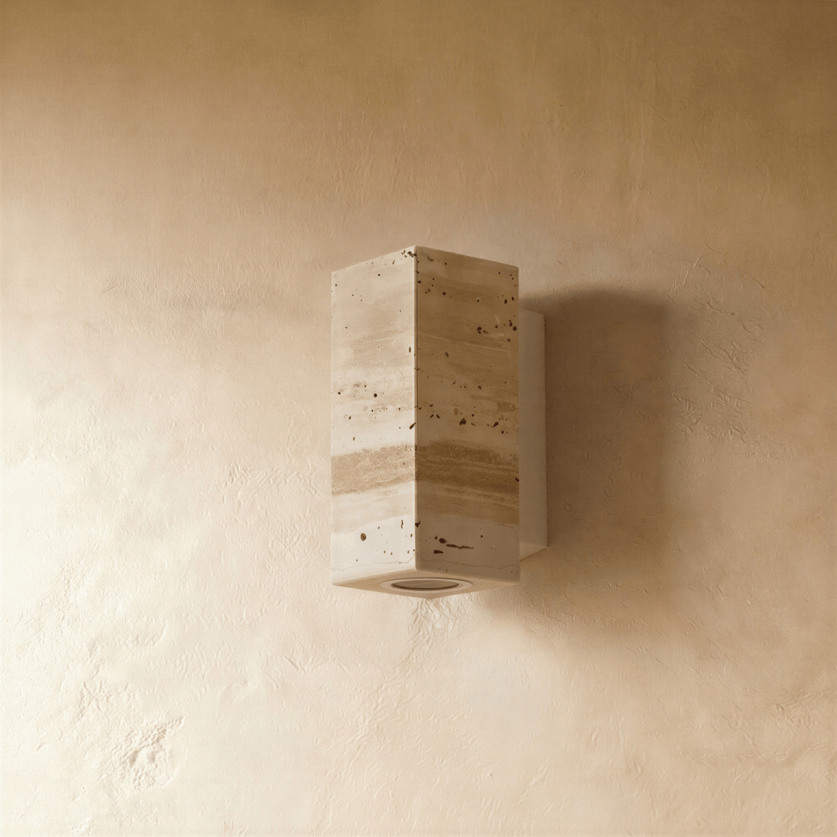 The Clérachic wall lamp's rectangular stone body viewed straight on against a plaster wall.