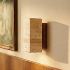A close-up of the Clérachic wall lamp's stone body and walnut base beside a framed painting.