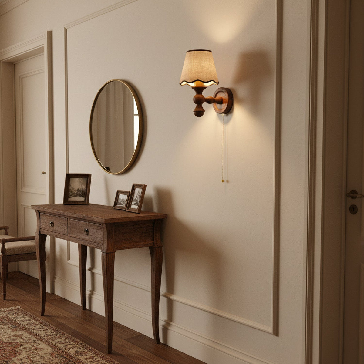 A Clérachic walnut wall light in a hallway beside a round mirror, above a slim wooden console table.