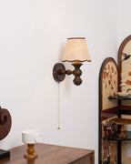 Clérachic walnut wall light seen from the side, with a pull chain and an arched painted panel at the right.
