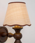 Close view of the brass-toned fitting under the shade and the turned walnut arm on this Clérachic wall light.