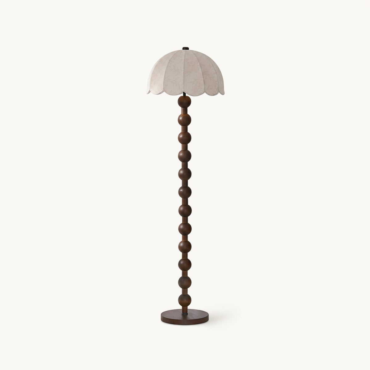 Floor lamp with a scalloped dome shade in beige fabric, a stem of stacked walnut balls and a round dark base, on white; a Clérachic design.