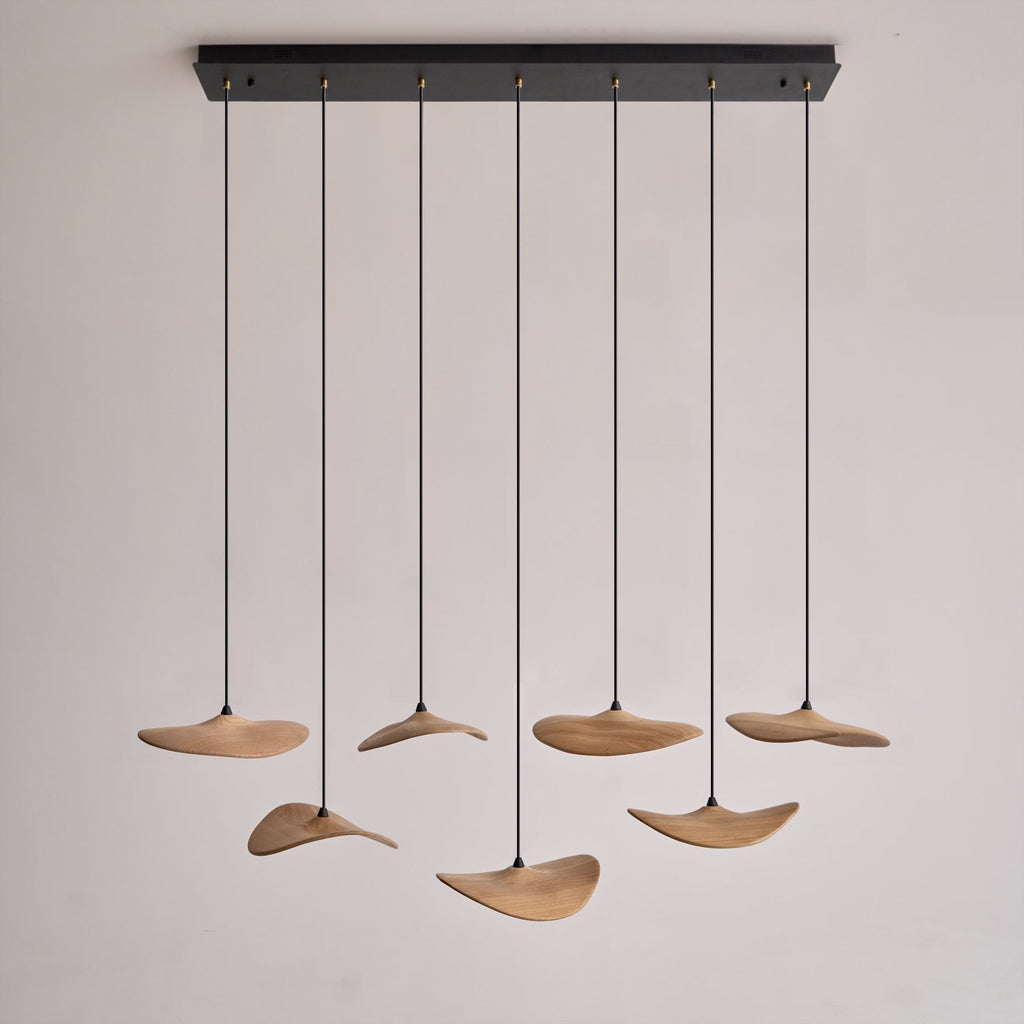 Seven Clérachic leaf pendants hanging from a long black rectangular canopy, on a plain pale background.