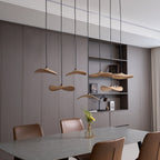Wide view of Clérachic wooden leaf pendants over a grey dining table, with built-in shelves and brown leather chairs.