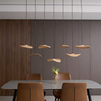 Clérachic leaf pendants lit in staggered rows against a ribbed timber wall, above a table with a flower vase.