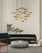 Cluster of Clérachic leaf pendants in a tall living room, over a round coffee table and a dark green curved sofa.