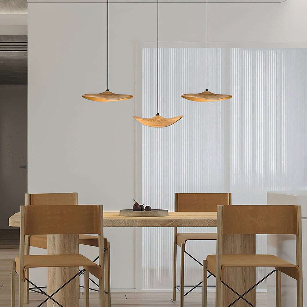 Three Clérachic leaf pendants above a light oak dining table with chunky chairs, in front of a pleated white screen.