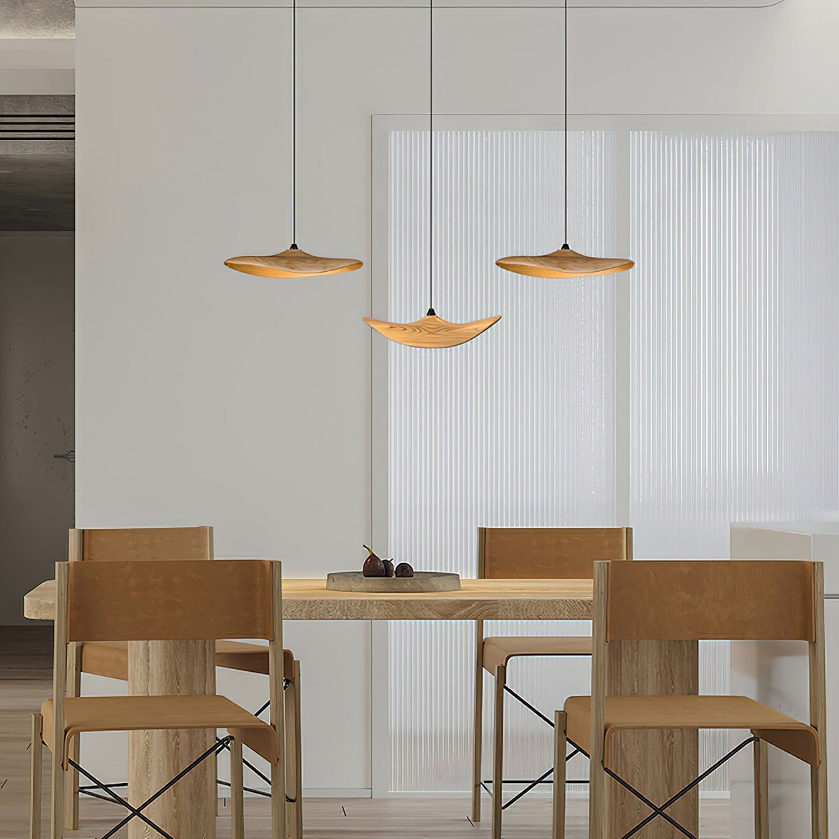 Three Clérachic leaf pendants above a light oak dining table with chunky chairs, in front of a pleated white screen.