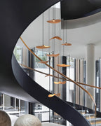 Clérachic leaf pendants hung at many heights alongside a sweeping black spiral staircase with a timber handrail.