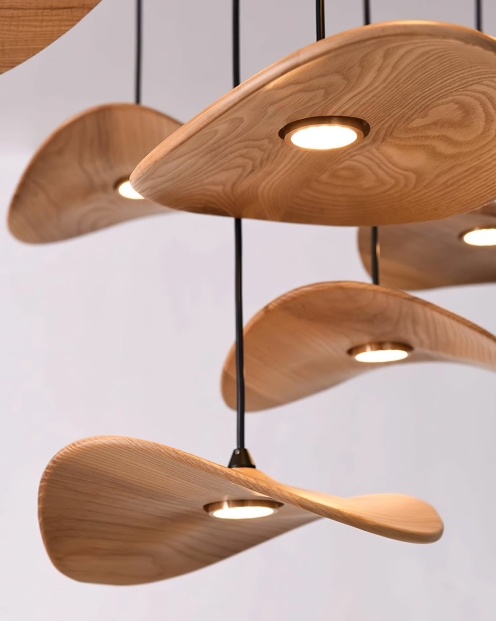 Close view of the pale ash grain on Clérachic leaf pendants, each with a small round brass-rimmed light underneath.