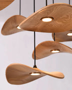 Close view of the pale ash grain on Clérachic leaf pendants, each with a small round brass-rimmed light underneath.