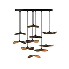 Cluster of ten Clérachic leaf pendants in walnut colour hung from a black bar canopy, with a warm glow below.