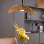 Clérachic wooden leaf pendant lit from beneath, above a vase of yellow flowers, with a shelf and desk lamp behind.