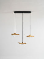 Three Clérachic wooden leaf pendants on a black oval canopy, hung at different heights against a plain grey wall.