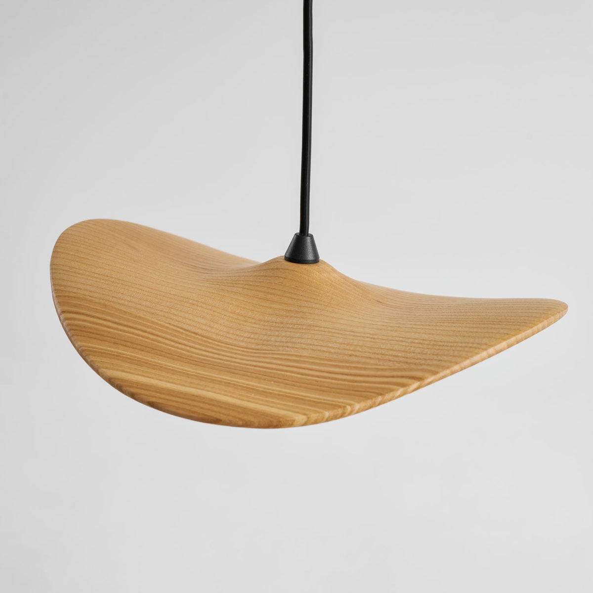 Close view of the striped ash grain on one curved Clérachic wooden leaf pendant and its black cord.