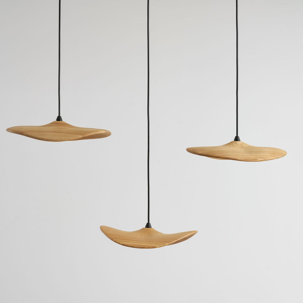 Three Clérachic leaf pendants at staggered heights against a light grey wall, seen close without the canopy.