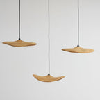 Three Clérachic leaf pendants at staggered heights against a light grey wall, seen close without the canopy.