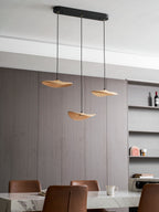 A Clérachic three-leaf pendant over a marble table, with a shelving unit with bottles and a pink arched ornament.