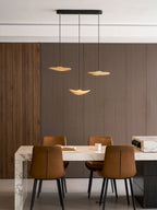 Three Clérachic leaf pendants hung over a marble-edged table with leather chairs, against dark wood panelling.