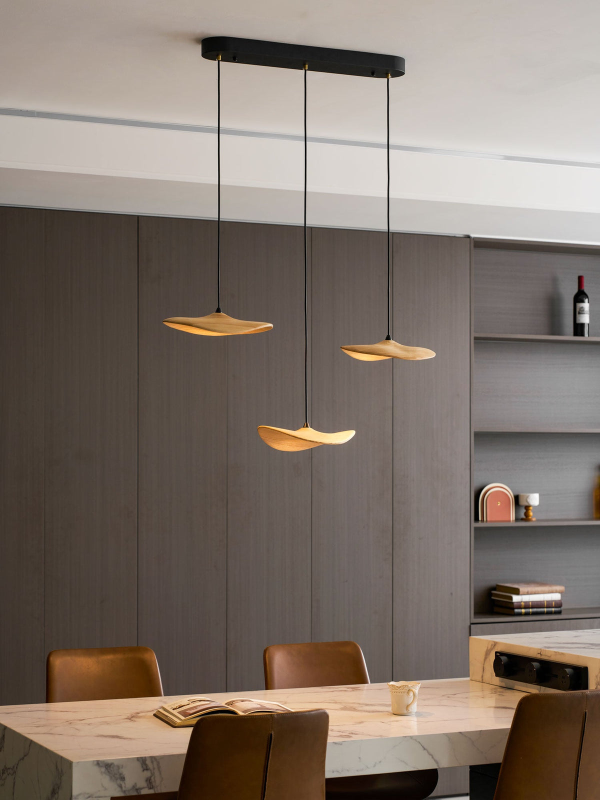 Clérachic three-leaf pendant on an oval black canopy above a marble table, beside a shelf with a wine bottle.