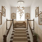 A Clérachic wood-sphere pendant cluster hanging in a stairwell, under a round ceiling plate, above a carpeted staircase and an arched window.