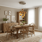 A Clérachic pendant of wooden spheres hung low over a farmhouse dining table, in a cream room with woven chairs and framed botanical prints.