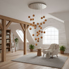 A Clérachic cascade of wood spheres on long cords from a round ceiling plate, in a loft room with timber beams and an arched window.