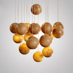 A Clérachic pendant with a cluster of natural wood spheres on thin cords, photographed on a light grey backdrop.