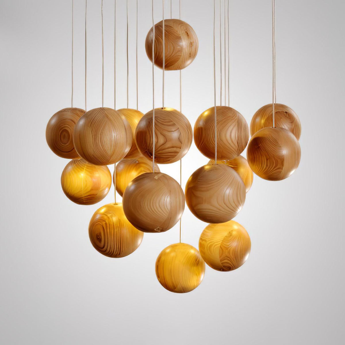 A Clérachic pendant with a cluster of natural wood spheres on thin cords, photographed on a light grey backdrop.