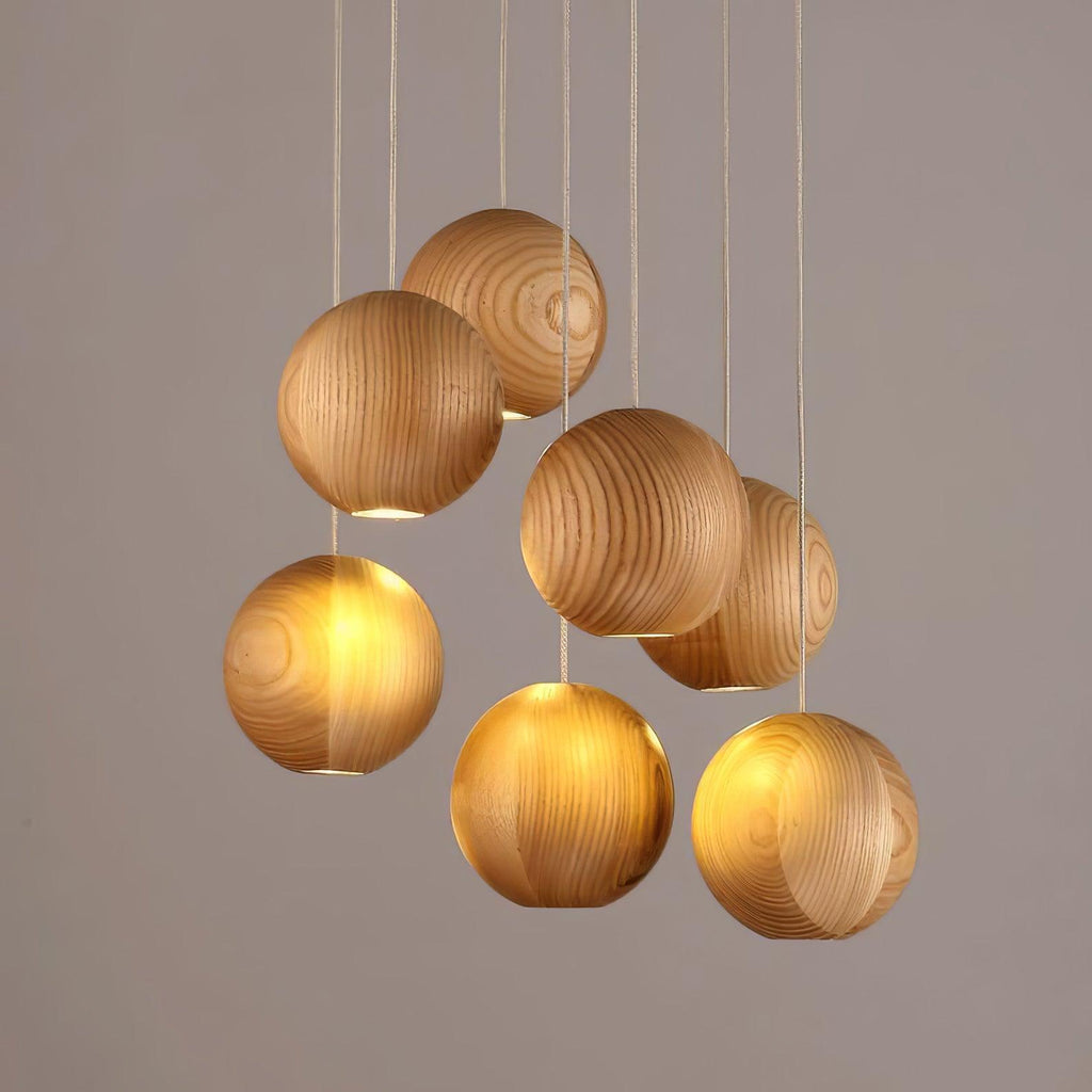 A smaller Clérachic wood-sphere pendant with spheres at staggered heights, lit from below against a soft grey backdrop.