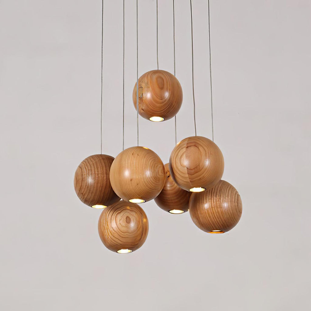 Wood spheres hang at different heights on this Clérachic pendant, each with a small light at its base, against a pale grey backdrop.