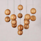 An unlit Clérachic pendant with wood spheres at staggered heights in two clusters, on a pale grey backdrop.