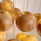Close view of the wood grain on this Clérachic pendant's spheres, with the thin cords entering each one through a small hole at the top.