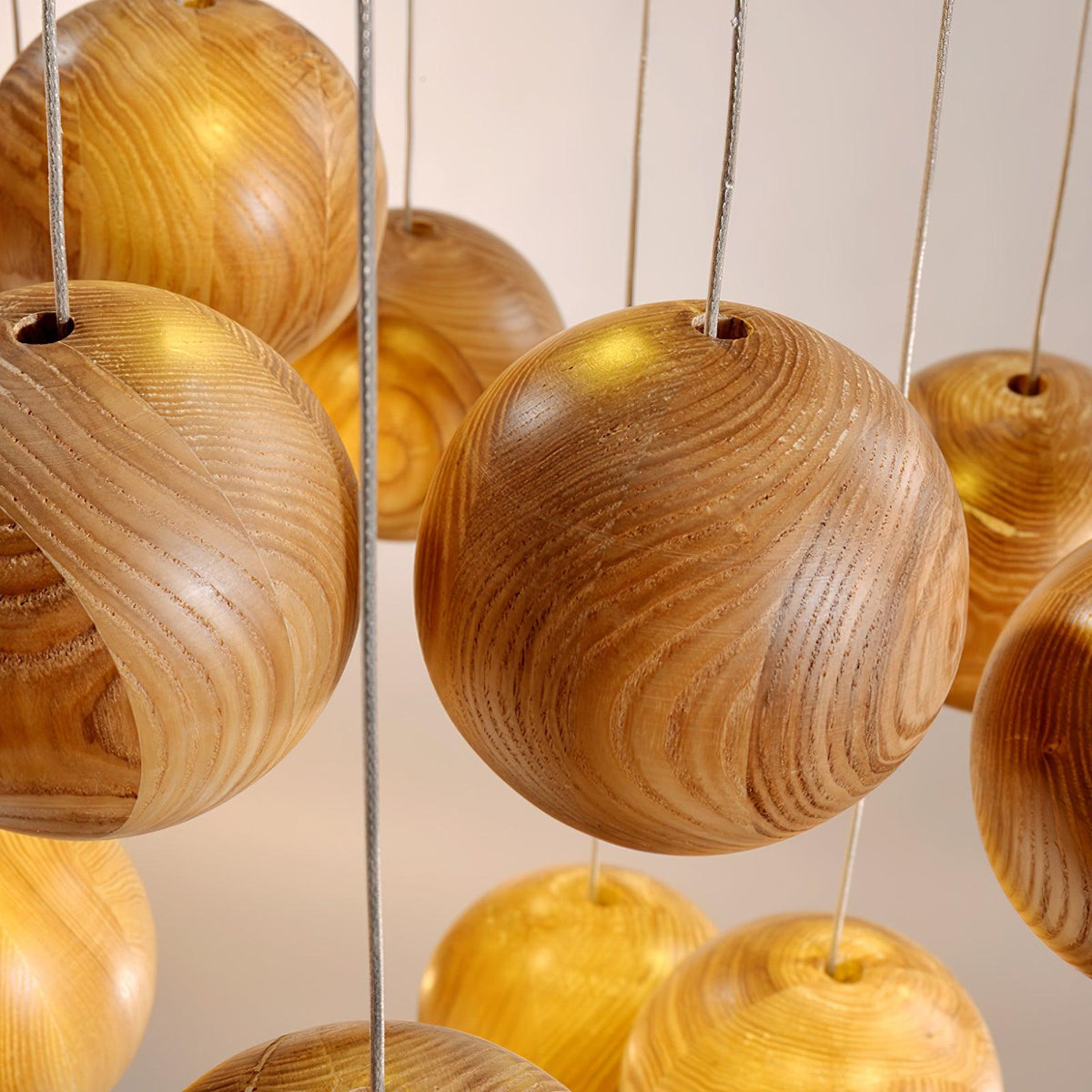 Close view of the wood grain on this Clérachic pendant's spheres, with the thin cords entering each one through a small hole at the top.
