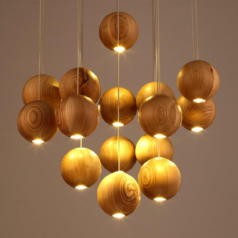 A Clérachic pendant of glowing wood spheres at varied heights, seen up close against a warm taupe wall.