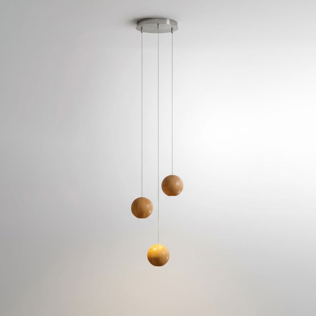 A three-sphere Clérachic wood pendant on a small round ceiling plate, one sphere glowing warm below two unlit spheres.
