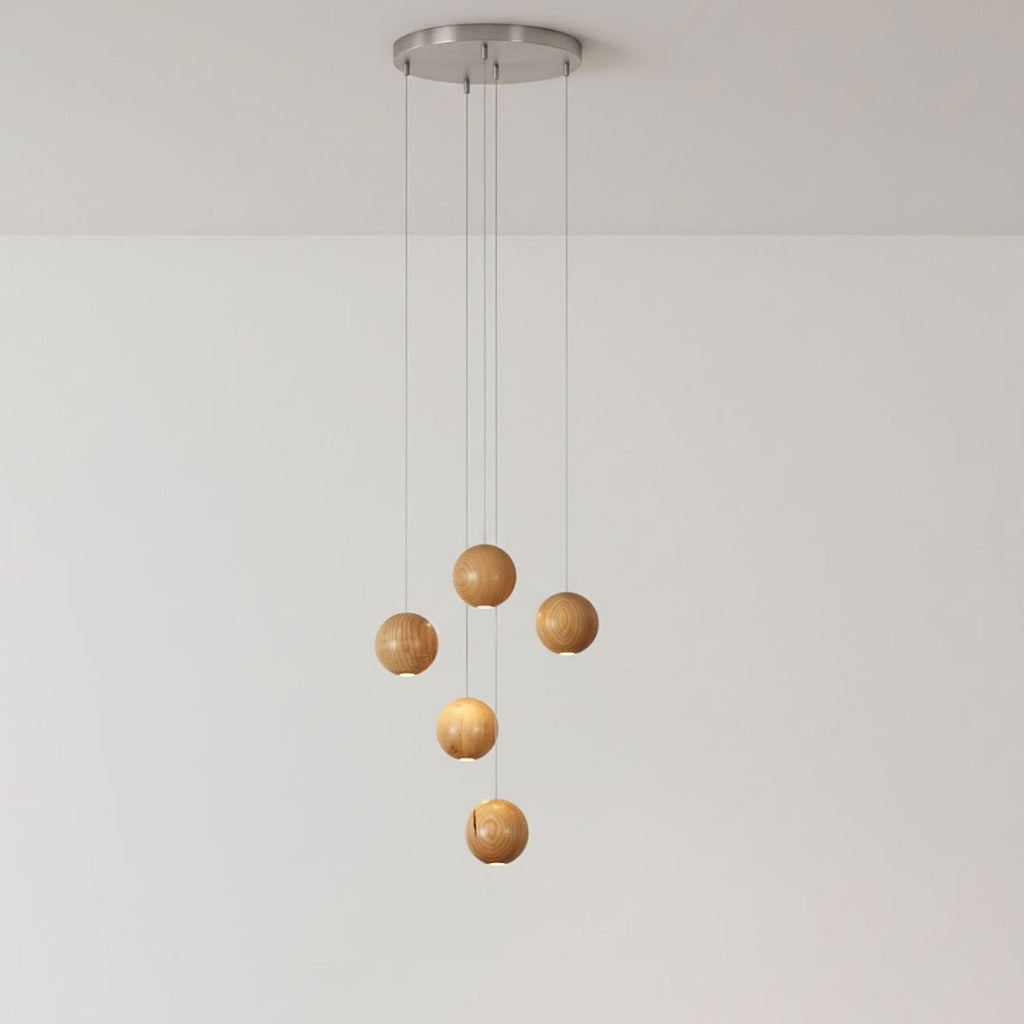 A five-sphere Clérachic wood pendant on a round brushed-metal ceiling plate, two spheres lit and three unlit, against a pale wall.