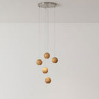 A five-sphere Clérachic wood pendant on a round brushed-metal ceiling plate, two spheres lit and three unlit, against a pale wall.