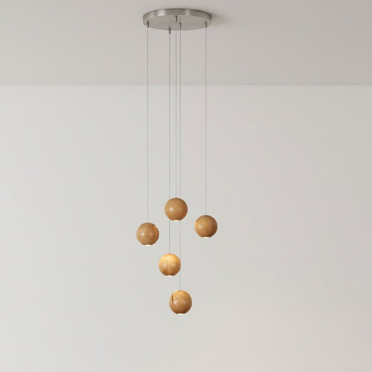 A five-sphere Clérachic wood pendant on a round brushed-metal ceiling plate, two spheres lit and three unlit, against a pale wall.