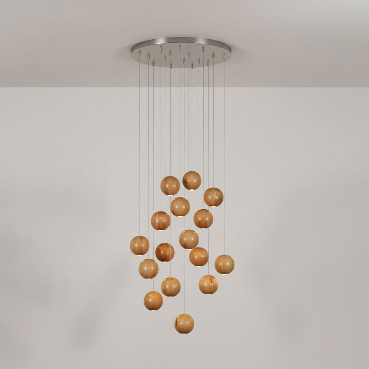 A Clérachic pendant of wood spheres under a round brushed-metal ceiling plate, in a pale grey room.